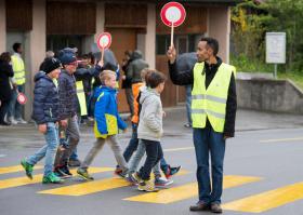 道路に立って「児童横断中」のサインを掲げる難民申請者