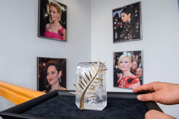 Il trofeo della palma d oro e sullo sfondo quattro fotografie di attrici.