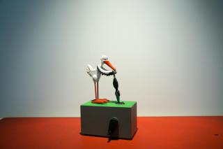 Model bird holding a press drill standing on a box with wind up key