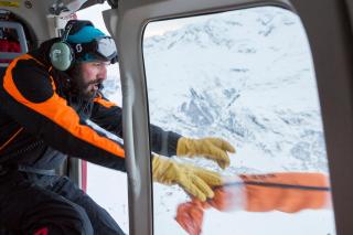 Viktor Perren, de Air Zermatt, arroja explosivos por la ventana para crear una avalancha controlada