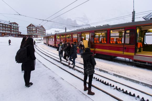 Asians tourists and a train by the Jungfrau railway in the Bernese Alps, Switzerland.