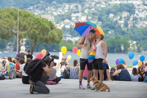LGBT parade with kissing couple and rainbow balloons