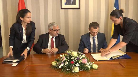 Swiss and Kosovo government representative signing a social security document