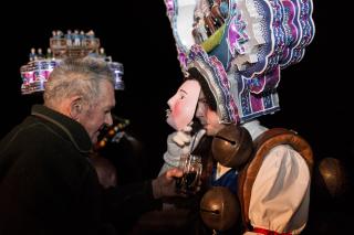 Ein Herr gibt einem Silvesterklaus unter der Maske zu trinken