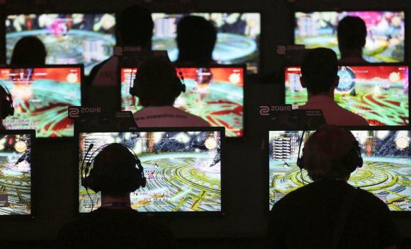 Visitors play computer games at the Gamescom fair in Cologne