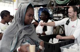une femme devant deux volontaires de médecins sans frontières qui distribuent des sacs