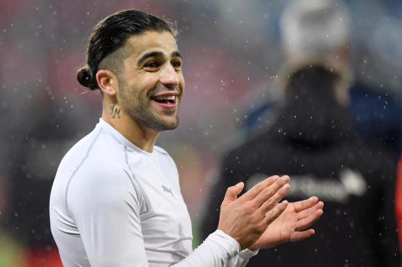 Ein lachender Fussballspieler mit weissem Pullover klatscht in die Hände.