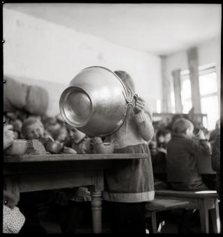 Una niña come la sopa escolar directo de la cazuela.