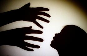 shadow of adult hands coming at face of a child