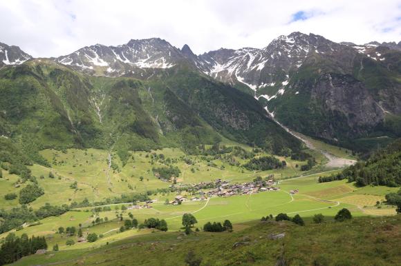 vallata con un villaggio circondato da verdi montagne