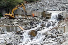 una scavatrice ai bordi rimuove le pietre ai bordi di un torrente