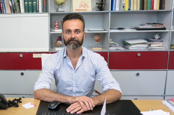 Il medico Massimiliano La Fauci nel suo studio, seduto davanti alla scrivania.