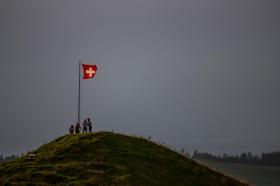 Schweizer Fahne und vier Wanderer auf einem Hügel