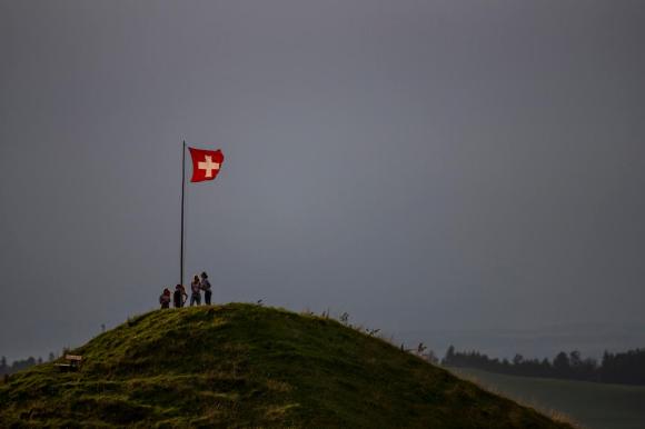 bandera suiza y cuatro personas en lo alto de una colina.