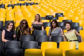 Five women sitting on black and yellow chairs