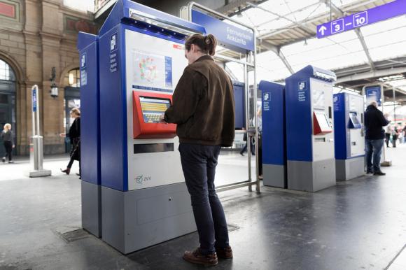 Un hombre compra un boleto de tren en una máquina expendedora.