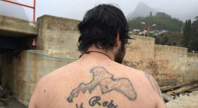Imagen de un hombre con un tatuaje de la isla Robinson Crusoe en la espalda.