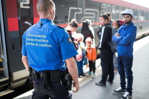 Una guardia di confine e un gruppetto di migranti che scendono da un treno.