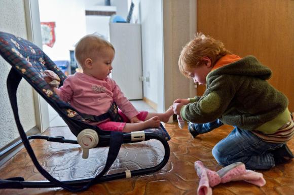 boy putting shoes on baby