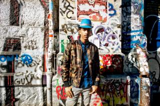 A young man in front of a graffiti wall