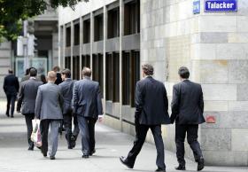 Funcionários de um grande banco suíço caminhando por uma avenida de Zurique.