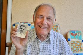 Alter Mann lächelnd mit Schwarzweiss-Foto von sich als Bub