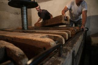 プレス板の上に木材の重しを置く作業
