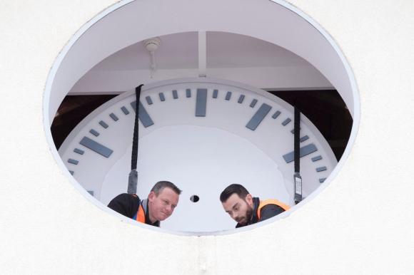 Dois operários consertando um grande relógio