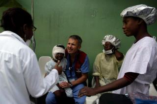 包帯を巻いた子供を抱える父親と医師たち