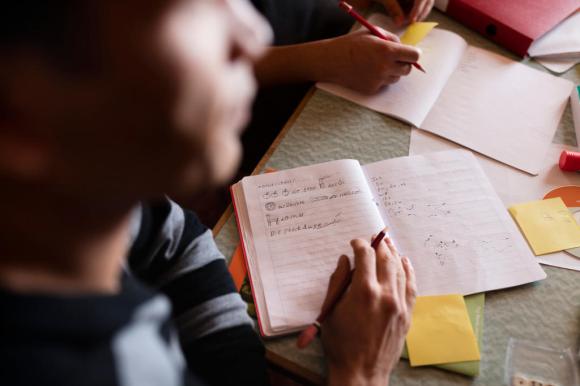 An asylum seeker takes notes in his notebook during German lessons in a converted classroom