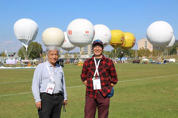 ガス気球をバックに立つ２人の日本人男性