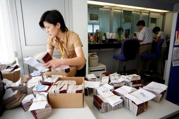 Chinesin bindet in einem Büro Pässe zu Bündeln zusammen