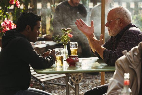 Dos hombres comparten mesa y conversación en un café