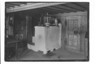 interior de uma velha casa de fazenda, com gravuras na porta e sistema de aquecimento