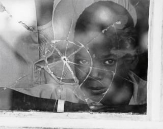 garoto através de uma vidraça com buraco de bala