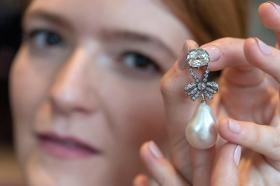 Una mujer muestra un broche con diamantes y una perla