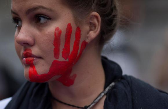 Una joven con una mano pintada en rojo sobre la mejilla