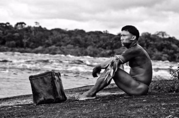 Un indígena sentado a la orilla del mar.