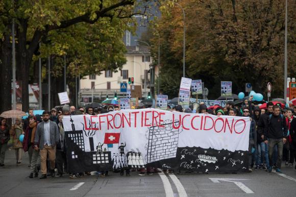 Una manifestazione a Chiasso a favore dei migranti: una folla con uno striscione Le frontiere uccidono
