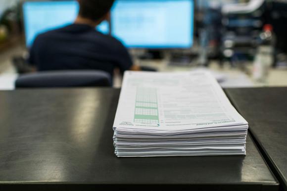 Pile of papers in front of a computer