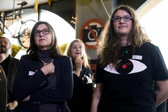 Zwei Frauen in Schwarz, jene rechts trägt ein T-Shirt mit grossem Auge drauf