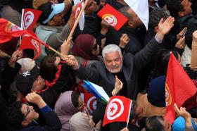 manifestazione in cui vengono sventolate bandiere tunisine.