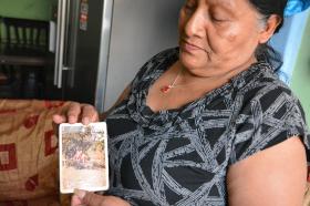 Mujer muestra una foto de su esposo desaparecido