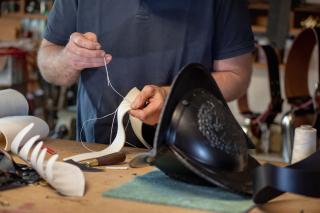 A craftsman works attentively on the Swiss guard helmet in his workshop