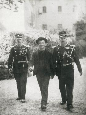 Foto en blanco y negro de Lucheni conducido por dos policías de Ginebra.