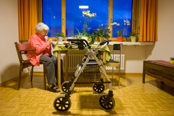 Elderly woman knitting and a walking frame