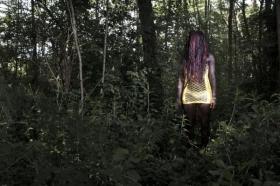 Imagen de Sarah (de espaldas) en el bosque, en la noche.