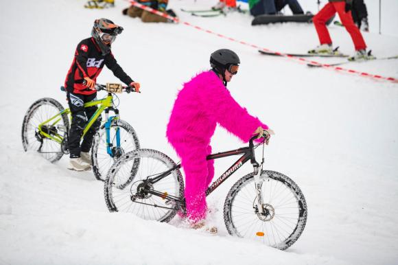 Two children in fancy dress on bicycles in the snow