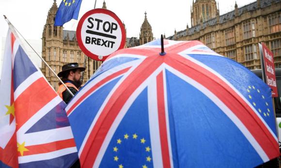 Schirm mit Union Jack, in dessen blauem Teil die Europasterne prangen. Dazu Schild STOP Brexit