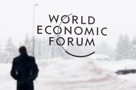 Homem desfocado na neve com painel de vidro do WEF em primeiro plano